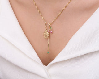 Gold necklace with a pendant on a person wearing a white top