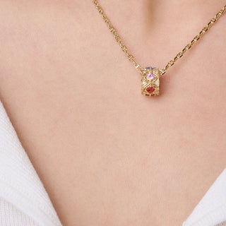 Gold necklace and earrings on a person wearing a white top against a neutral background
