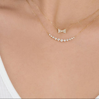 Woman wearing gold necklaces and earrings against a plain background