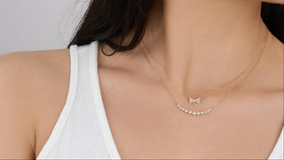 Woman wearing 18K gold & diamond necklaces against a plain background