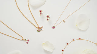 Gold jewelry set with necklaces and earrings on a white background with flowers.
