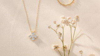 Gold necklace, ring, and pendant on a beige background with dried flowers.