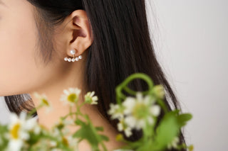 Close-up of a person wearing earrings with flowers in the foreground