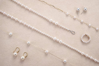 Pearl jewelry set including necklace, earrings, and ring on a beige background