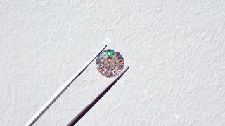Diamond held by tweezers on a light gray background